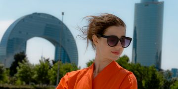 Woman in orange dress with sunglasses and buildings