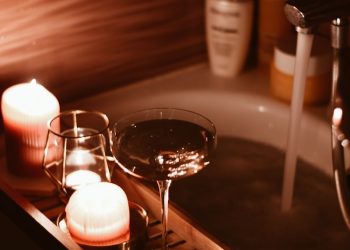 A bath tub filled with candles and a wine glass