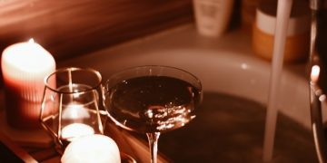 A bath tub filled with candles and a wine glass