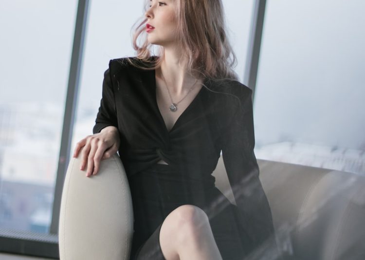 woman in black blazer sitting on white chair