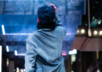 a man standing on a sidewalk in front of a billboard