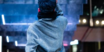 a man standing on a sidewalk in front of a billboard