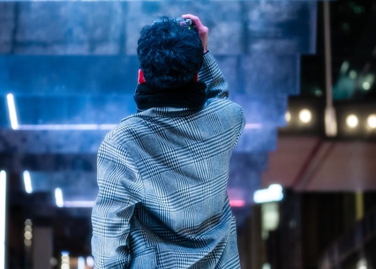 a man standing on a sidewalk in front of a billboard