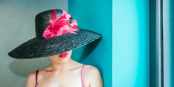 woman wearing pink camitop and black straw hat