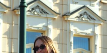 A woman is standing on a railing in front of a building