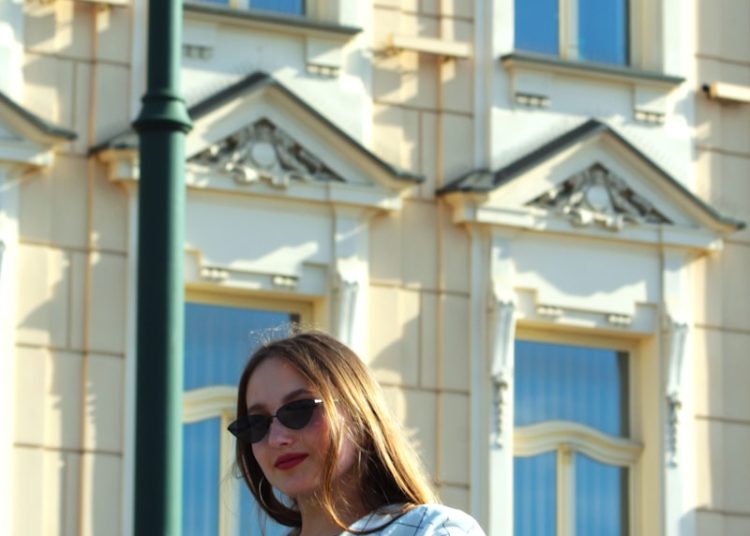 A woman is standing on a railing in front of a building