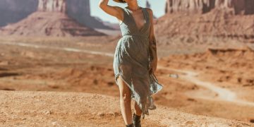 woman in grey dress standing on brown sand during daytime