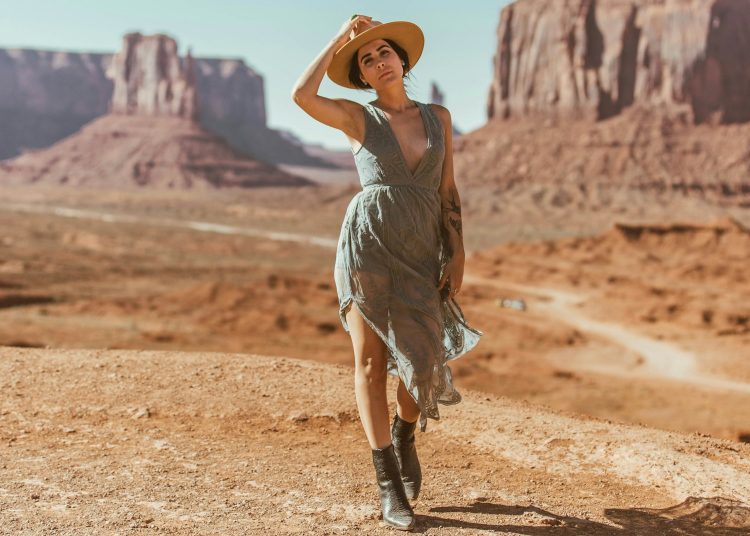 woman in grey dress standing on brown sand during daytime