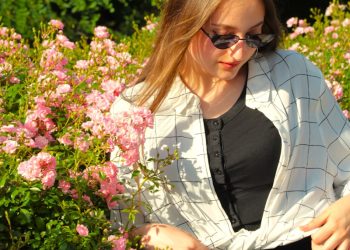 A woman sitting on a bench in front of flowers