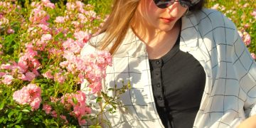 A woman sitting on a bench in front of flowers