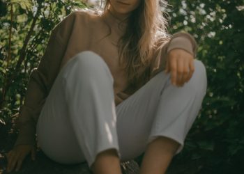 a woman sitting on a rock in the woods