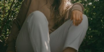 a woman sitting on a rock in the woods