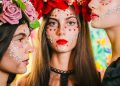 three women with painted faces and flowers on their heads