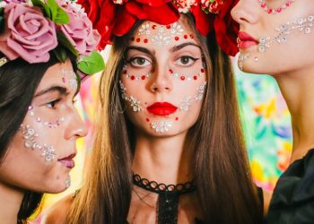 three women with painted faces and flowers on their heads