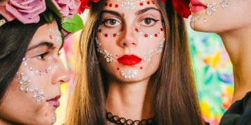three women with painted faces and flowers on their heads