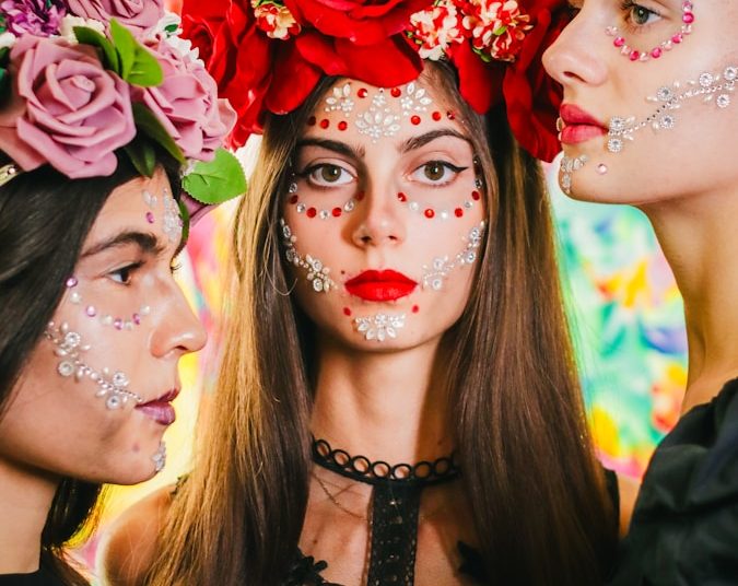three women with painted faces and flowers on their heads